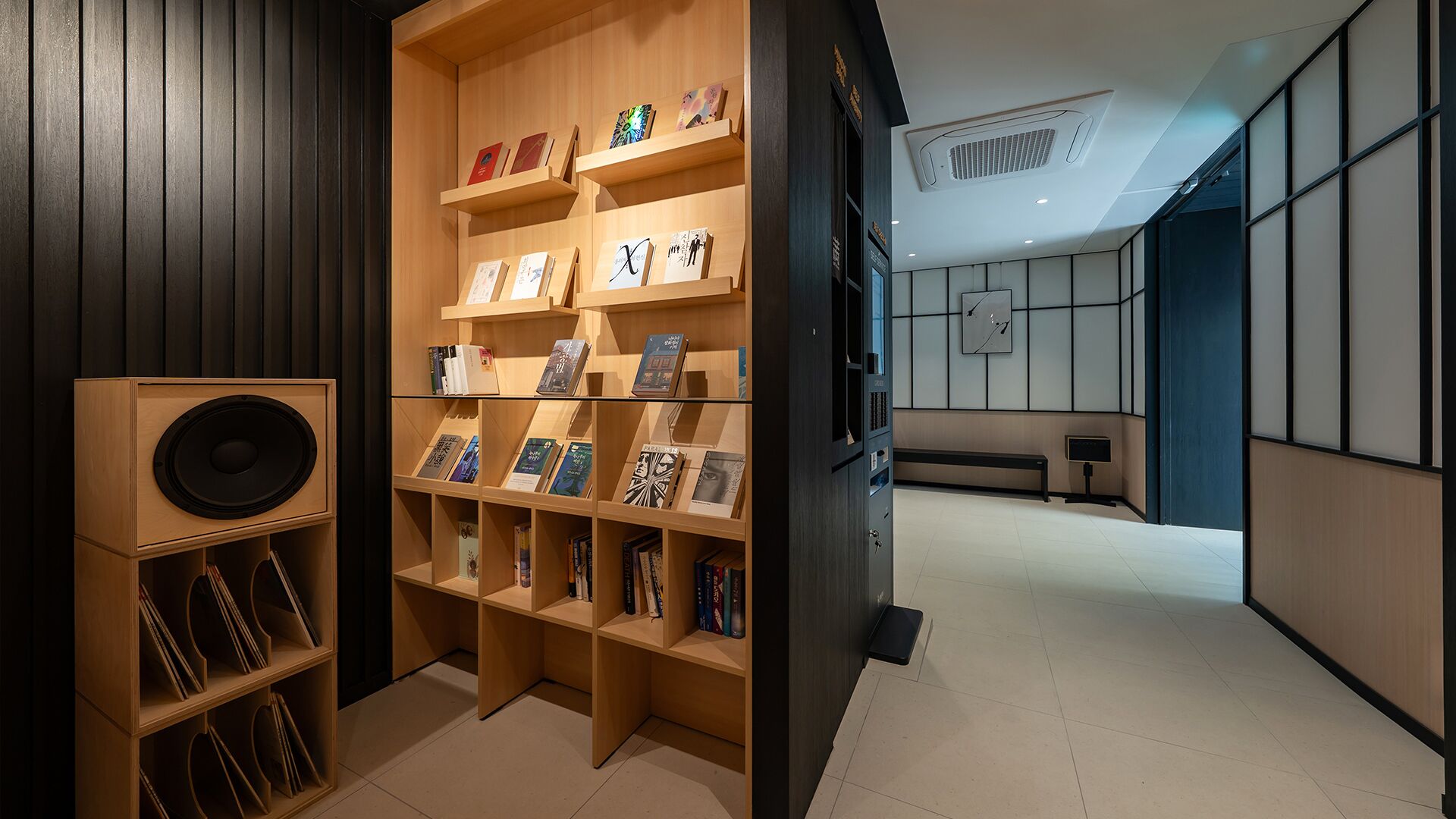 A modern interior with a wooden bookshelf displaying books and a speaker.