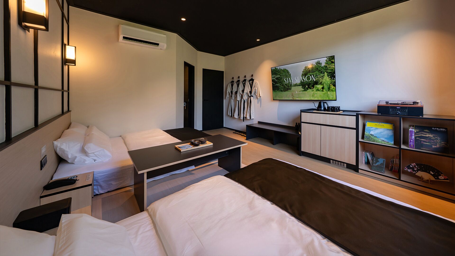 Een moderne hotelkamer met een bed, nachtkastje en een aan de muur bevestigde televisie.