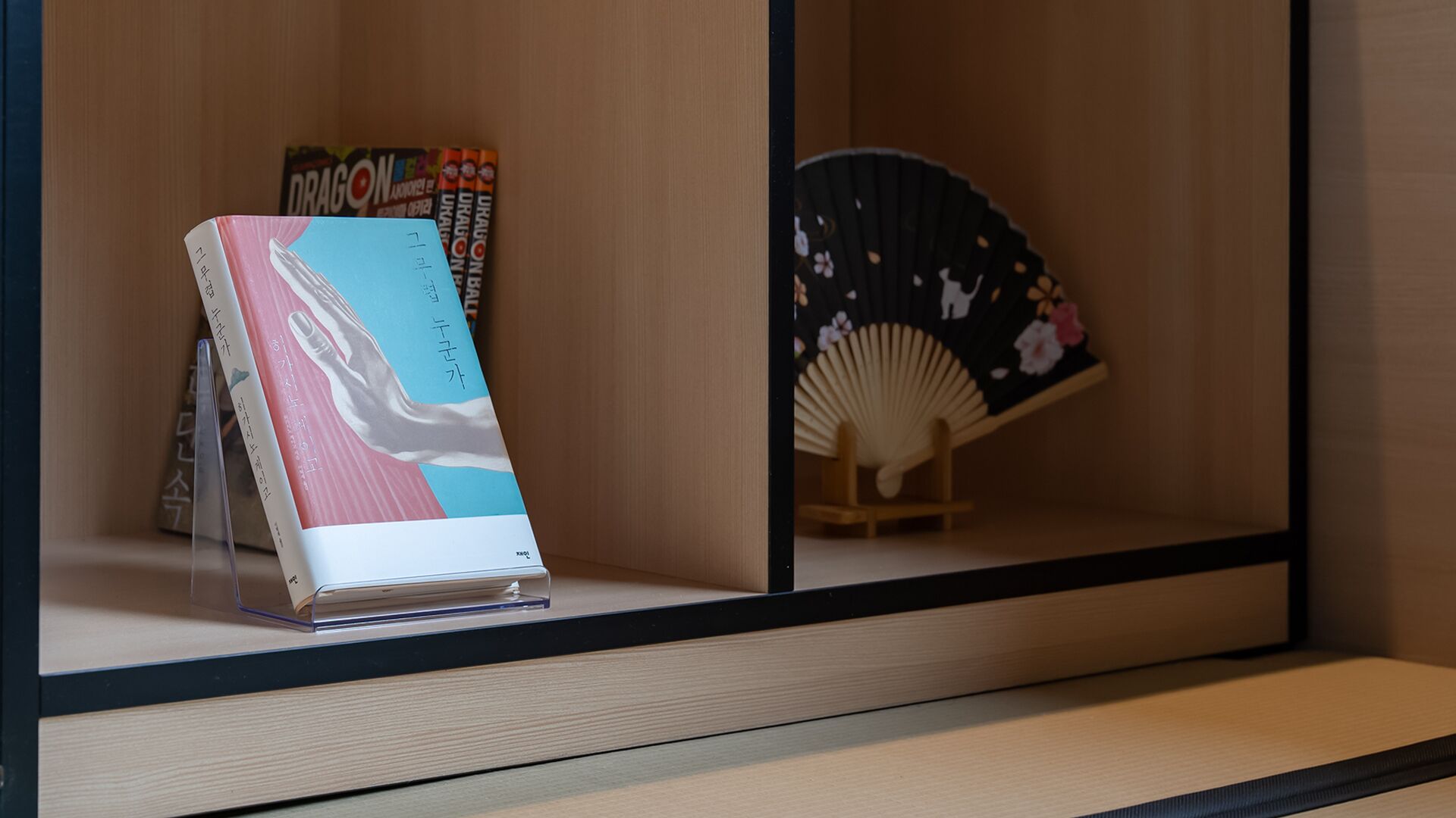 Una exhibición de libros con un libro titulado 'Dragon' y un abanico al fondo.