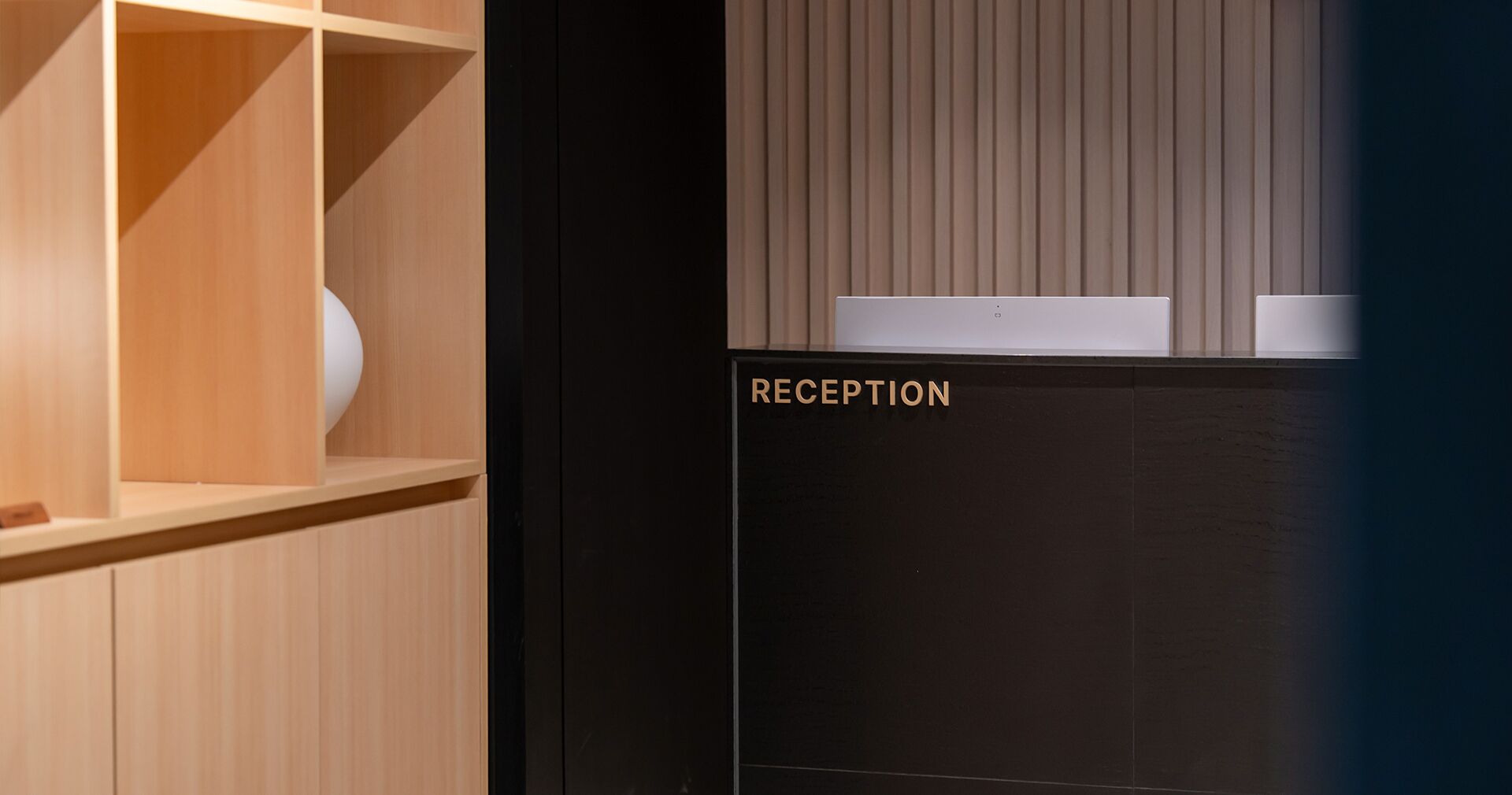 Un espace d’accueil avec un bureau en bois et un comptoir noir.