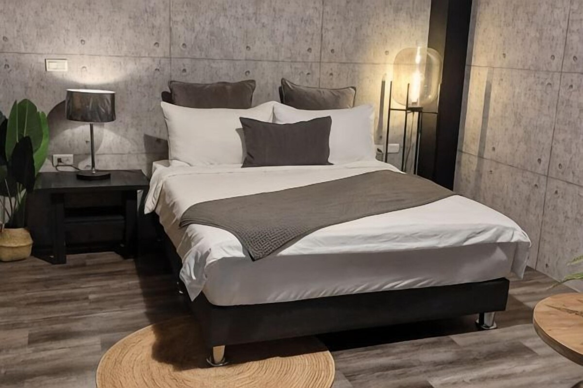 Un dormitorio moderno con una cama, mesitas de noche, lámparas y una alfombra redonda.