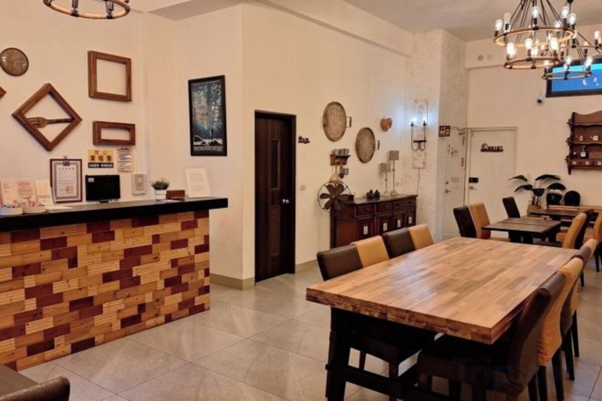 A restaurant with a wooden bar and a long dining table with chairs.