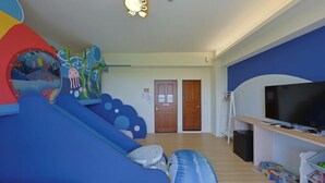 Ein Zimmer mit einem blauen Spielbereich, einem Fernseher und einer Tür.