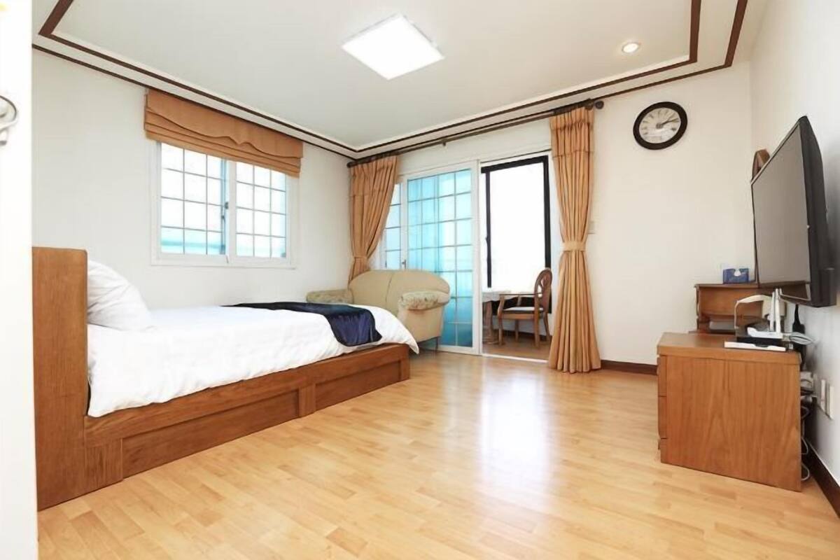 A hotel room with a bed, a desk, a television, a window, and a door leading to a balcony.
