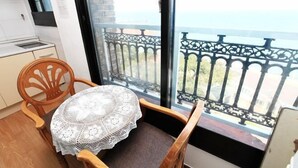 A small kitchen with a window, a wooden chair, and a table with a lace tablecloth. - seaview (Jeju)