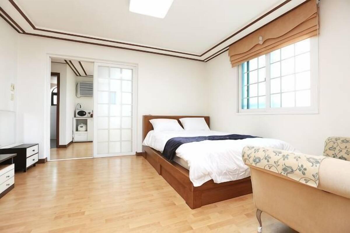 A bedroom with a wooden bed, a sofa, a desk, and a wardrobe.
