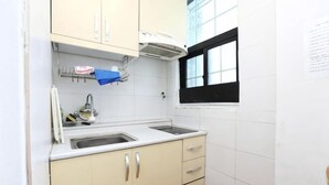 A small kitchen with a double sink, a window, and a trash bin. - seaview (Jeju)