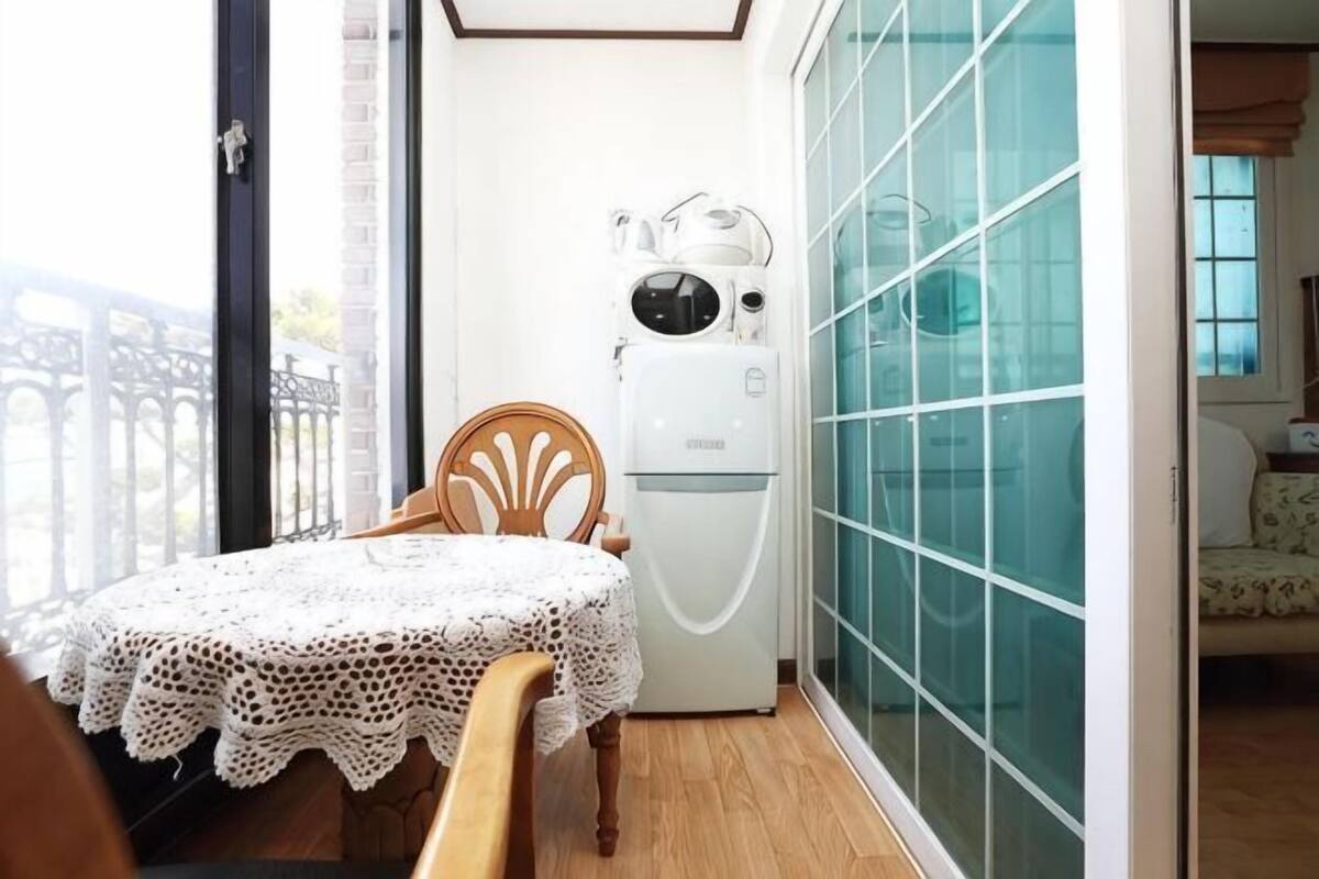 A small room with a table, chair, and a white appliance.