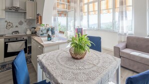 Una cocina moderna con comedor, que presenta una mesa con mantel de encaje, una planta en maceta y vistas al exterior a través de amplios ventanales.