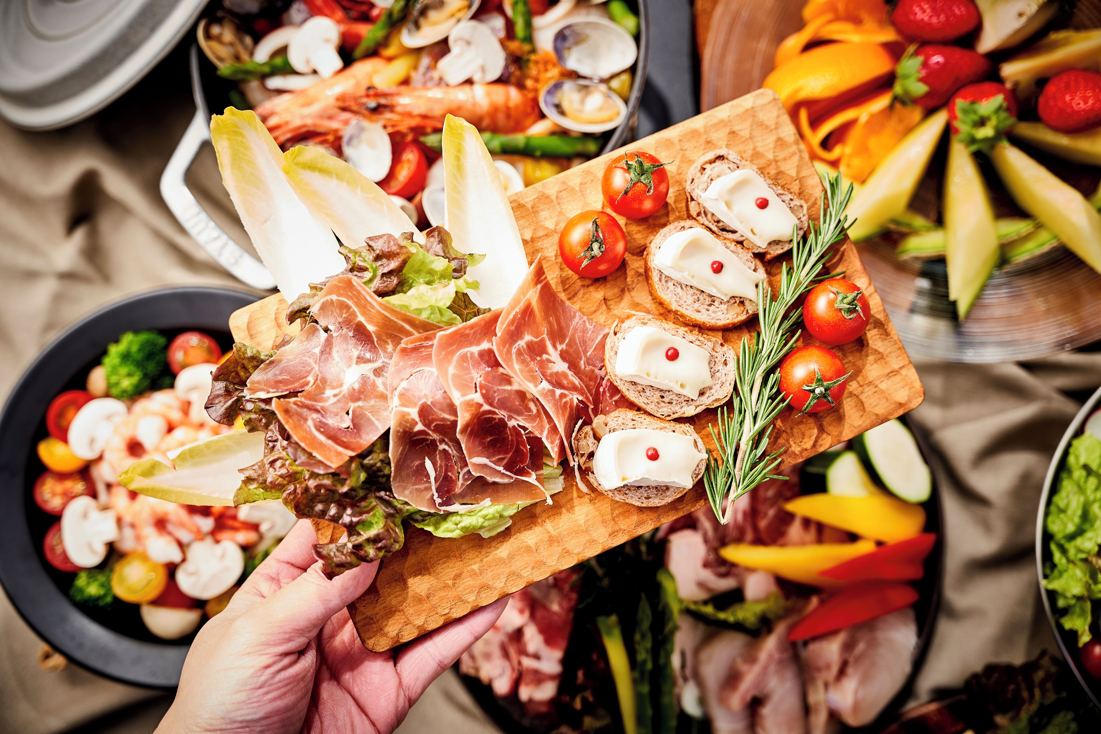 Un tagliere in legno con diversi alimenti, tra cui carni, formaggi e verdure.