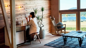 A cozy cabin interior with a wooden interior, a dining area, and a view of the sea. - glampoceanluxe umikumano (Taiji)