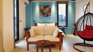 A modern living room with a sofa, a hanging chair, a painting, and a window. - Lafika｜Dao Villa (Yilan)