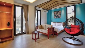 A modern room with a sofa, a hanging chair, a small table, and a bed. - Lafika｜Dao Villa (Yilan)