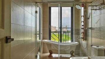 A modern bathroom with a bathtub, shower, and a large window offering a view of the outdoors.