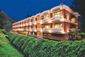 Hotel de vários andares com design moderno, com varandas e um jardim bem cuidado.