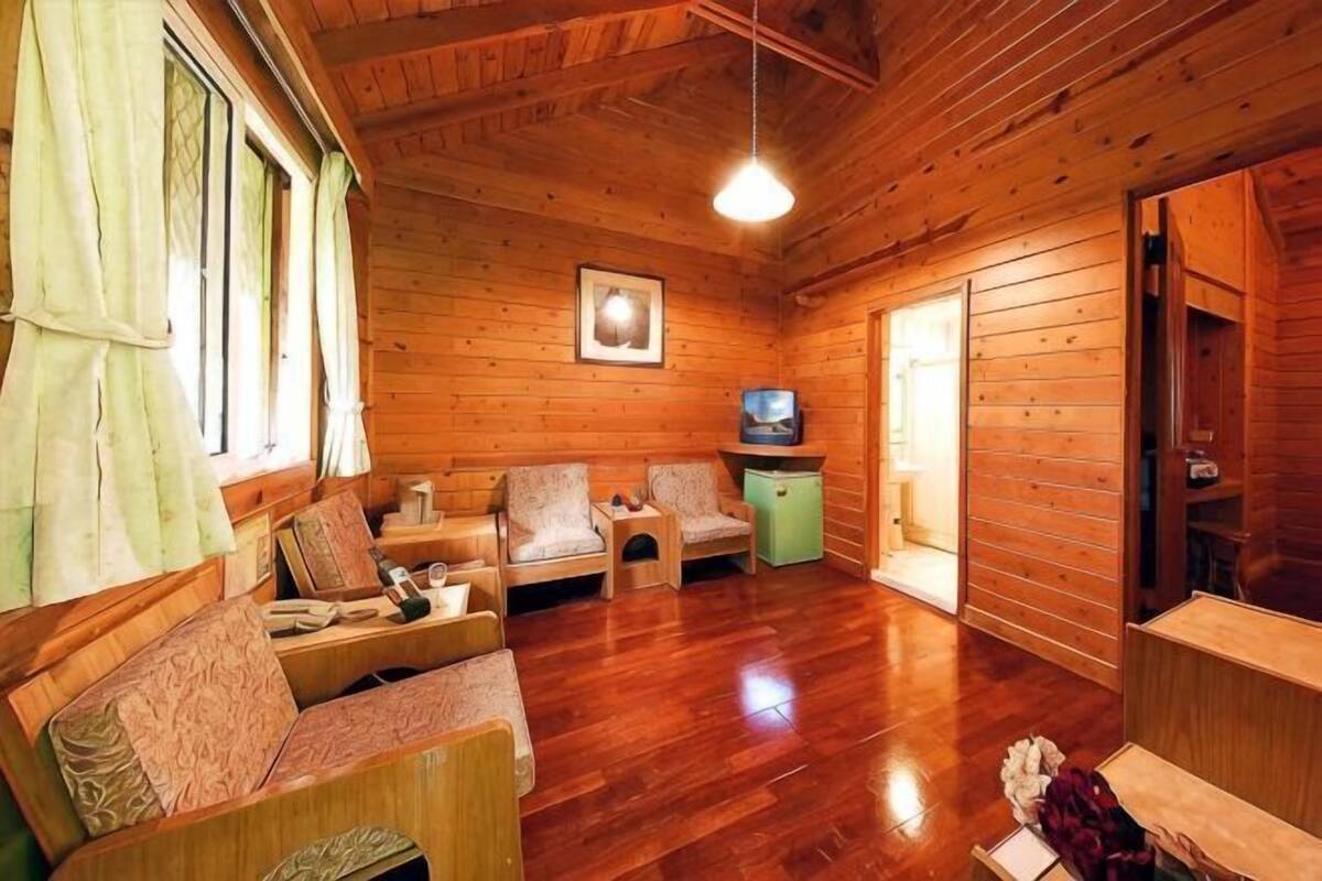 A wooden cabin interior with a sofa set, a television, and a small cabinet.