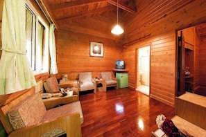 A wooden cabin interior with a sofa set, a television, and a small cabinet. - Sun Moon Lake Youth Activity Center (Nantou)