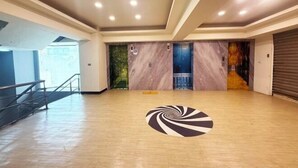 Un hall d’entrée spacieux et bien éclairé, doté d’un plancher en bois, d’un motif central en spirale et d’un escalier situé à gauche.