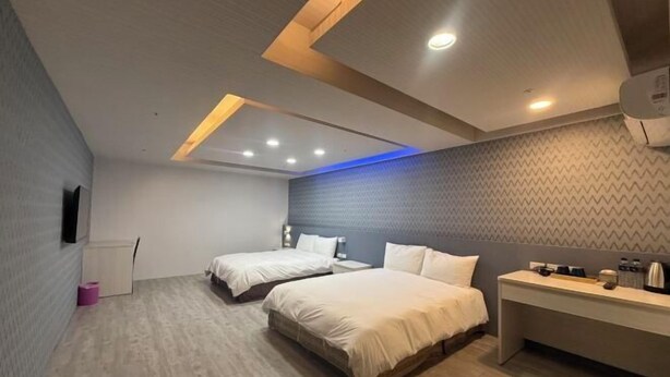Une chambre d’hôtel moderne équipée de deux lits, d’un bureau et d’un téléviseur à écran plat.