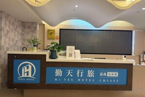 Una recepción con un logotipo, un letrero con caracteres chinos y un televisor de pantalla plana.