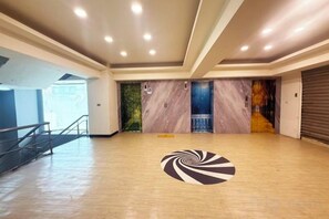Un espacio interior amplio con piso de madera, un diseño espiral en el suelo y una escalera que sube a un nivel superior.