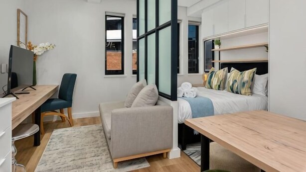 Une chambre d’hôtel moderne équipée d’un lit, d’un bureau, d’une chaise, d’un canapé et d’une télévision.