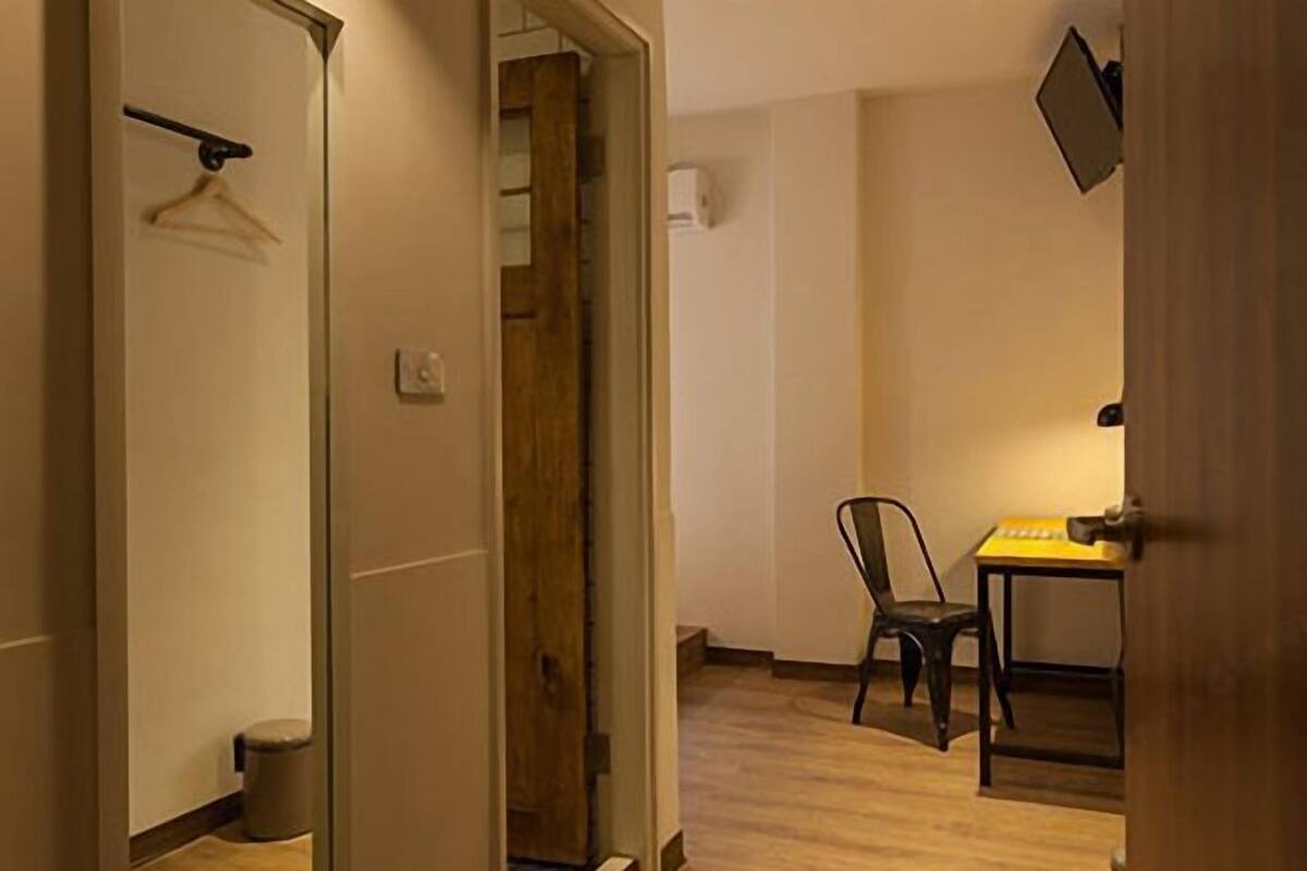 A room with a wooden floor, a chair, a table, a hanging coat rack, and a door.