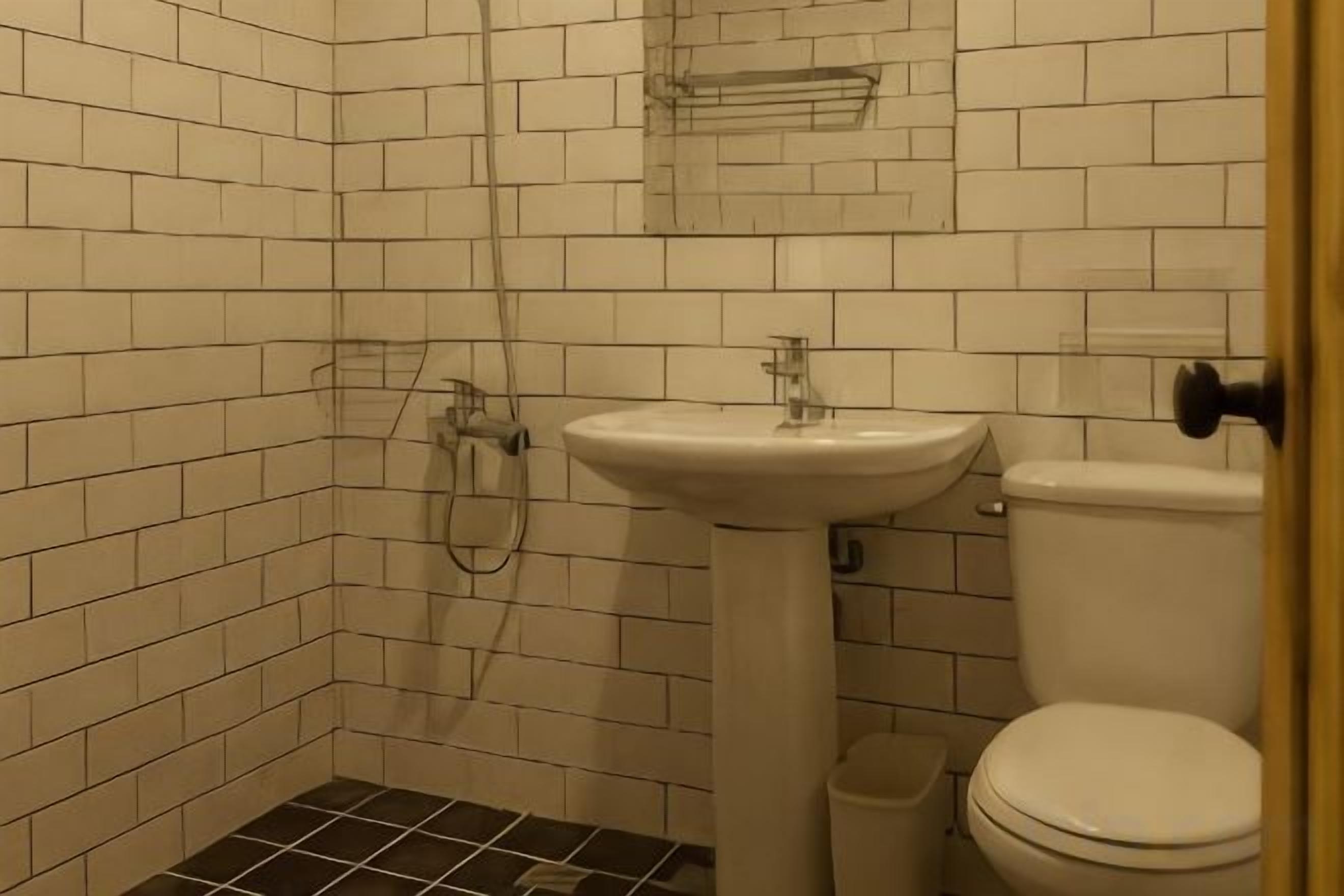 Un baño con paredes de azulejos blancos, un lavamanos blanco y un inodoro.