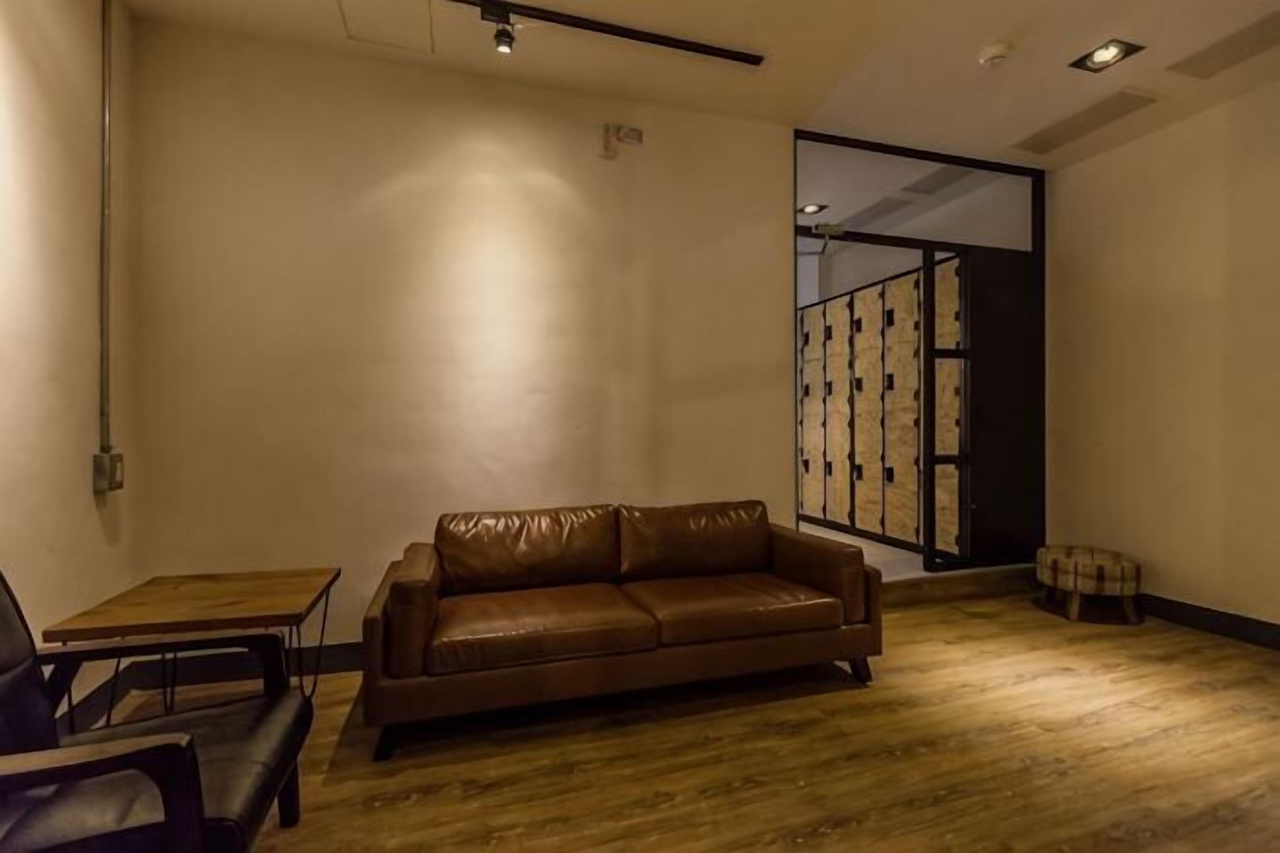 A room with a leather sofa, a small table, and a bench.