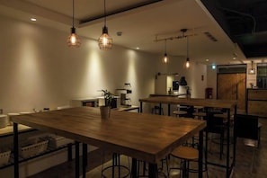 A modern dining area with wooden tables and hanging pendant lights. - Mini Voyage Hostel (Hualien)