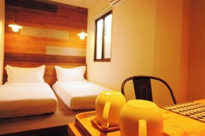 A hotel room with two beds, a wooden headboard, a window, and a tray with two mugs. - Mini Voyage Hostel (Hualien)