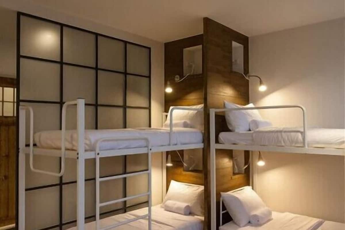 A bunk bed room with a wooden headboard, a wall-mounted mirror, and a light fixture.
