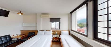Habitación de hotel con dos camas, un sofá, un televisor y ventana con vistas.