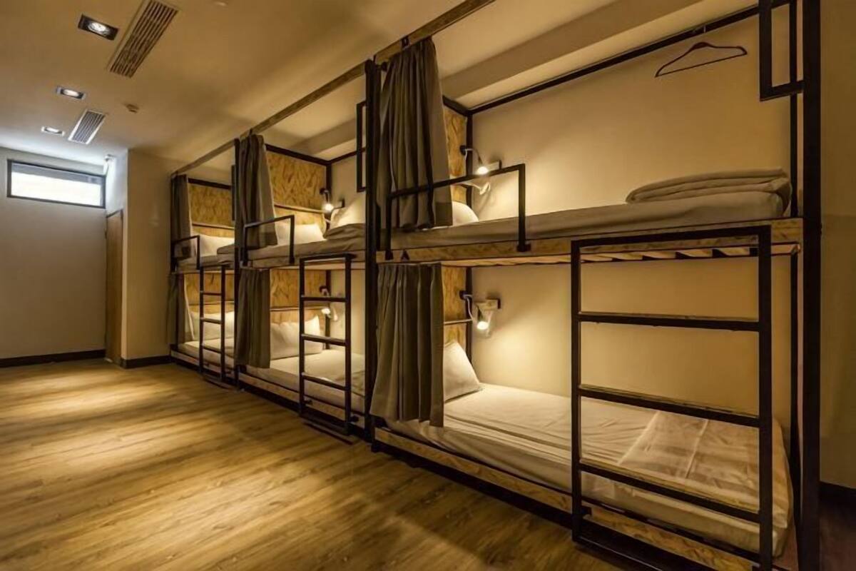 A room with bunk beds, a wooden floor, and a window.