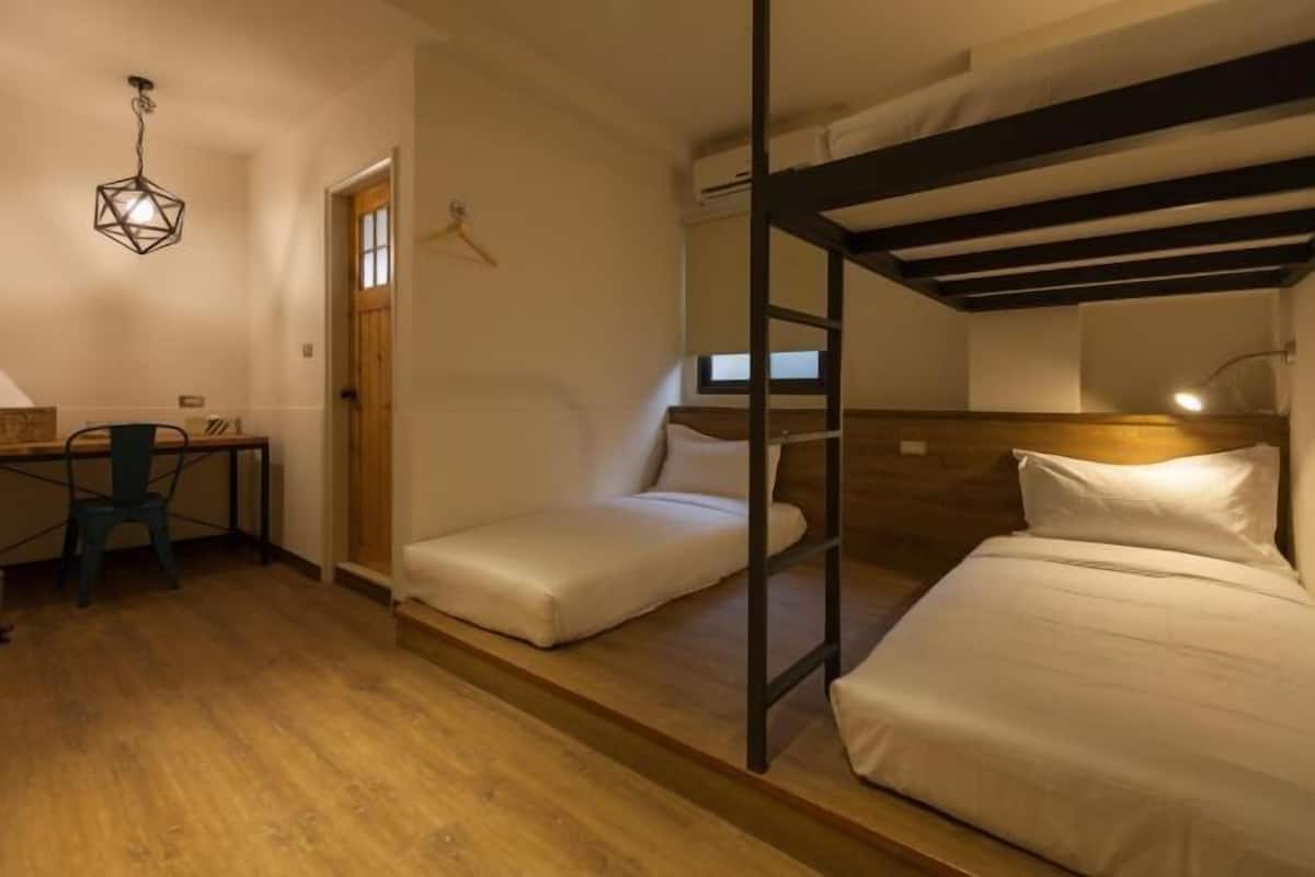 A compact room with bunk beds, a desk, and a chair.
