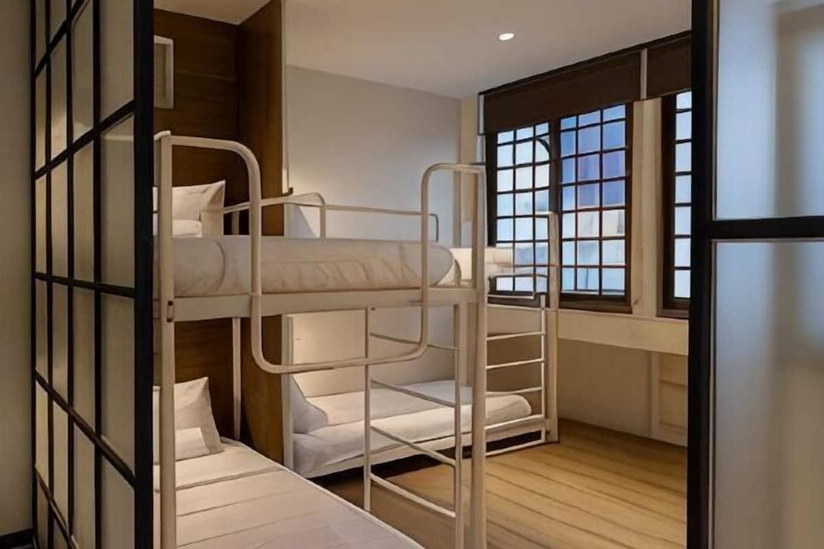 A bunk bed room with a window and wooden flooring.
