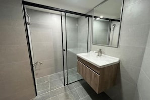 Une salle de bain moderne avec une douche à parois de verre, un meuble-lavabo en bois et un miroir au-dessus du lavabo.