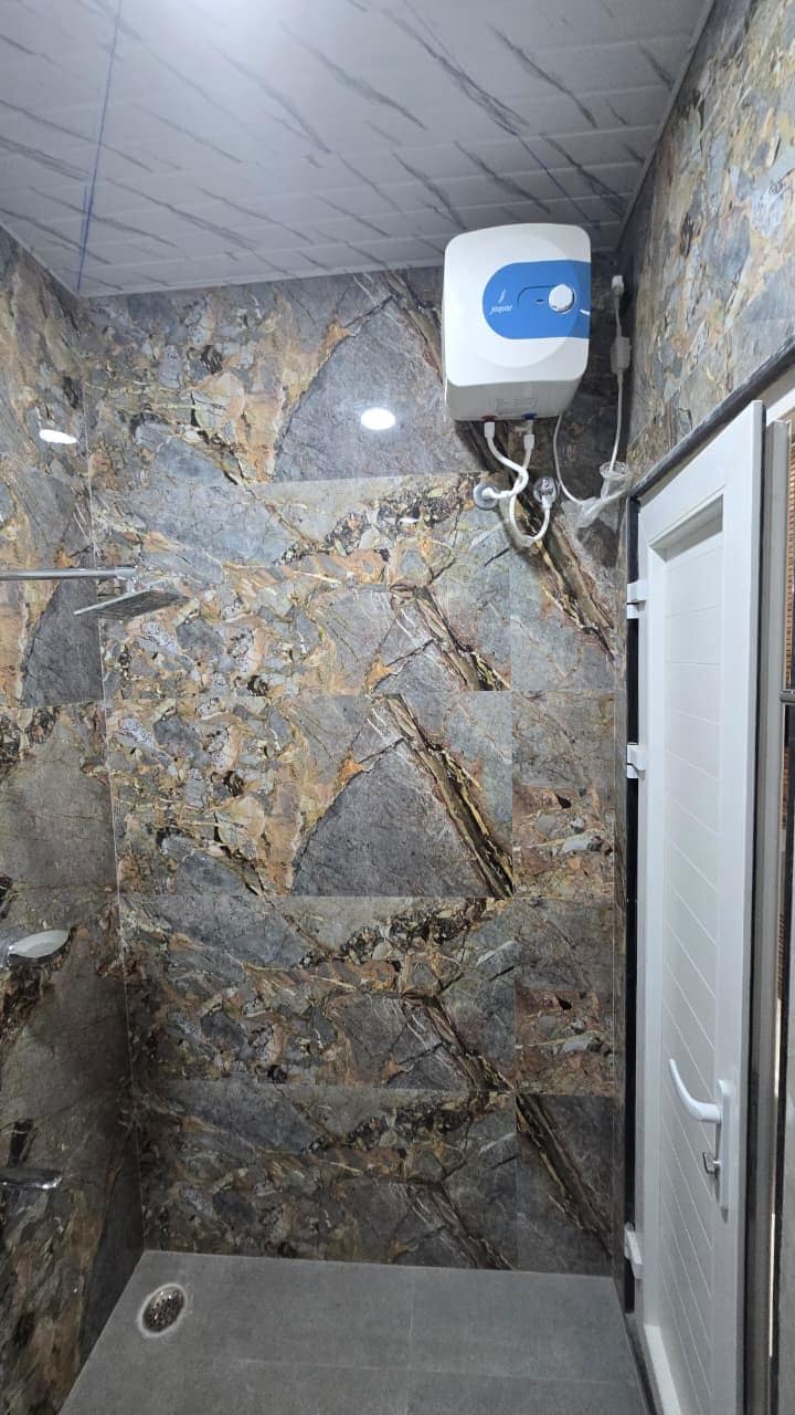A bathroom with a stone wall, a shower, and a toilet.
