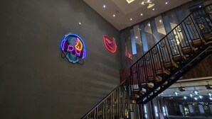 Ein modernes Interieur mit einer Treppe, einem leuchtenden Neon-Schädel und einem Chandelier.
