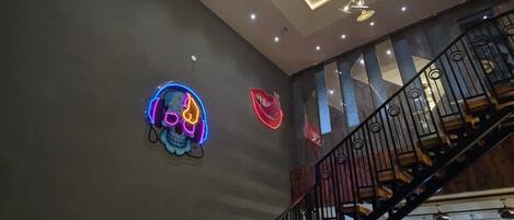 Un interior moderno con una escalera, un letrero de calavera neón y una araña.