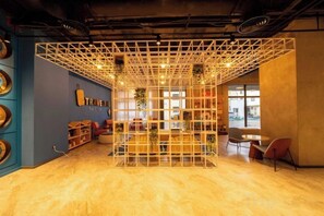 A modern interior with a geometric light fixture, a seating area with a table and chairs, and a wall with a sign. - Fullon Poshtel Penghu (Penghu)