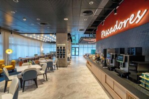A modern dining area with tables and chairs, a counter with a menu display, and a large illuminated sign. - Fullon Poshtel Penghu (Penghu)