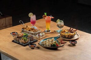 A wooden table with various dishes and drinks, including a salad, a bowl of fries, and a colorful drink. - Fullon Poshtel Penghu (Penghu)