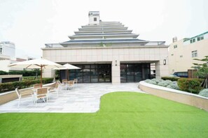 A modern building with a stepped facade, outdoor seating area, and a well-maintained lawn. - Fullon Poshtel Penghu (Penghu)