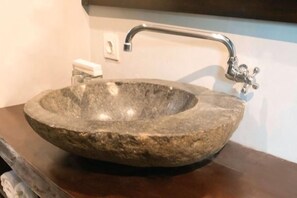 A stone sink with a modern faucet in a bathroom. - Me Villa Pererenan (Bali)