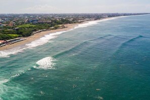 A coastal view with a beach, ocean, and distant buildings. - Me Villa Pererenan (Bali)