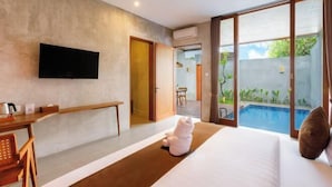 Quarto de hotel com cama, escrivaninha, televisão e vista para uma piscina.