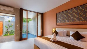 A bedroom with a bed, pillows, a nightstand, a painting, and a sliding glass door leading to an outdoor area. - Me Villa Pererenan (Bali)