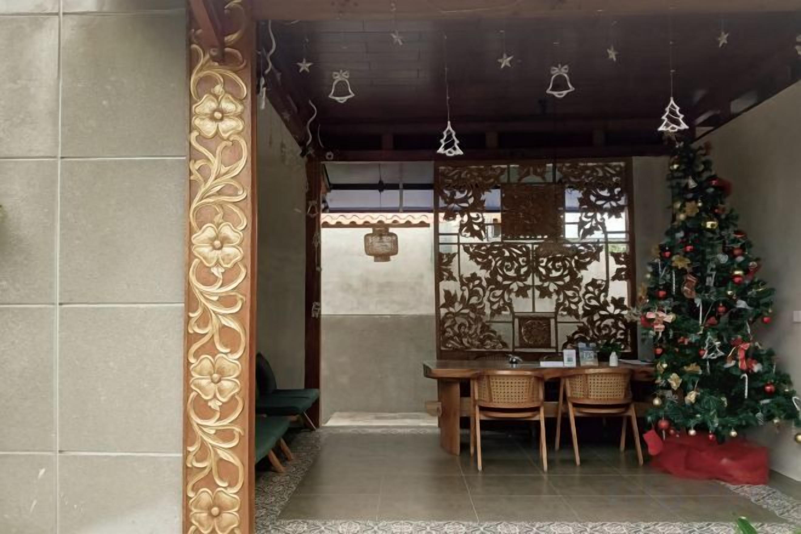 A room with a traditional design, featuring a wooden table and chairs, a Christmas tree, and decorative wall panels.