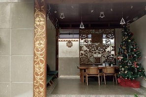 A room with a traditional design, featuring a wooden table and chairs, a Christmas tree, and decorative wall panels. - Me Villa Pererenan (Bali)